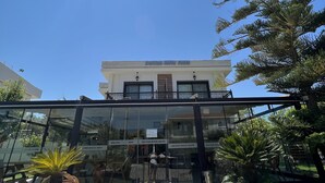 A hotel entrance with a glass facade, a red carpet, and potted plants. - Dalyan Risus Suite (Cesme)