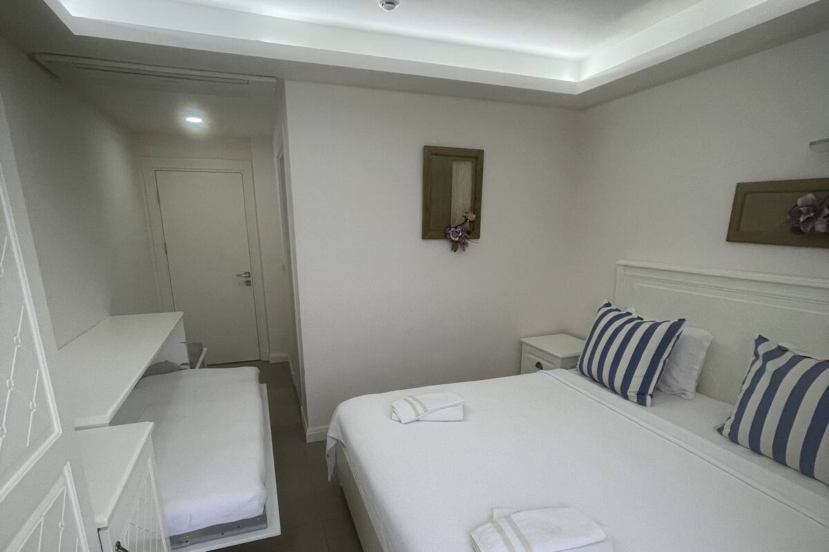 Habitación de hotel con cama, mesitas de noche, armario y espejo en la pared.
