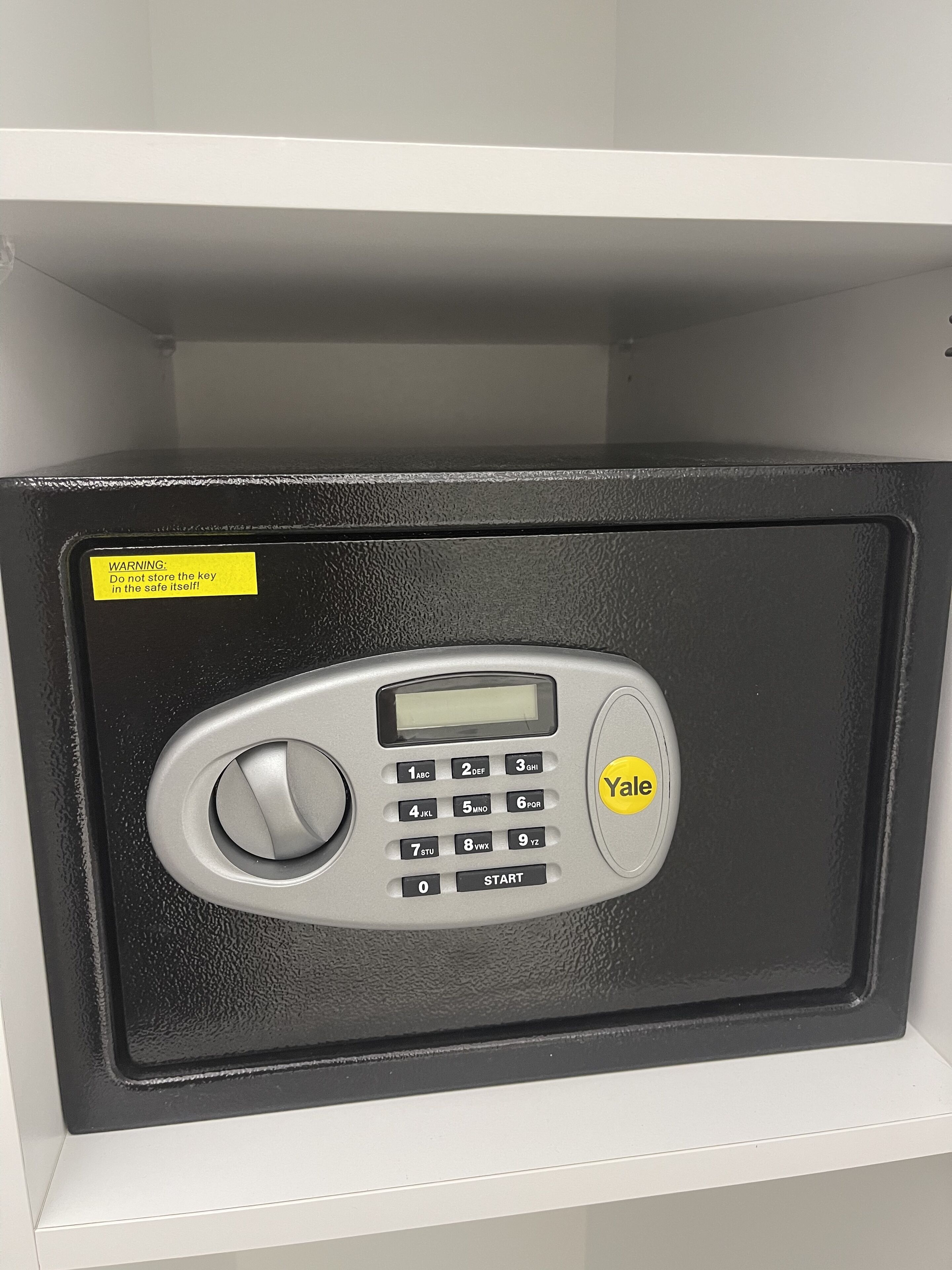 A Yale safe with a keypad and a digital display, placed on a shelf.