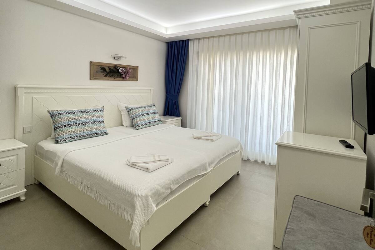 Un dormitorio moderno con una cama grande, una mesita de noche, un televisor y una lámpara en el techo.