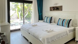 A spacious bedroom with a large bed, a sliding glass door to the balcony, and a small bedside table. - Dalyan Risus Suite (Cesme)