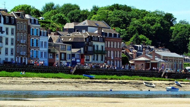 Een plaats aan de rivier met historische gebouwen, een zandstrand en boten.