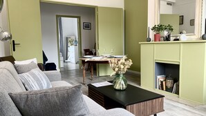 Een woonkamer met een bank, een bijzettafeltje en een eethoek met een tafel gedekt voor twee personen.
