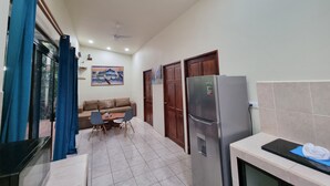 A modern kitchen with a refrigerator, a dining area with a table and chairs, and a living area with a sofa. - Romantic Villa Anturio at Pinilla Highlands with Amazing Canopy views (Guanacaste Province)