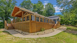 Eine Holzhütte mit einer Terrasse und einer überdachten Veranda, umgeben von Bäumen.