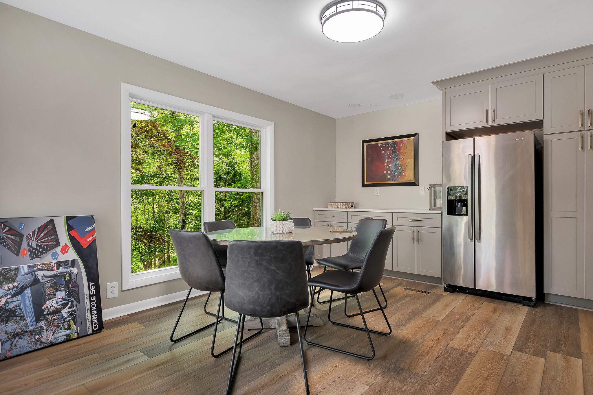 A modern kitchen with a large window, stainless steel appliances, and a dining area with black chairs.