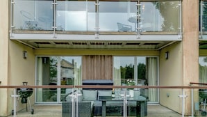 Une maison moderne à deux étages, dotée d’un balcon, de mobilier d’extérieur et d’un barbecue.