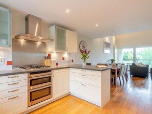 A modern kitchen with a central island, built-in ovens, and a dining area with a view.
