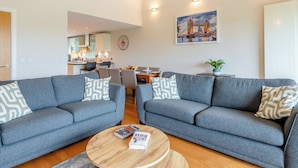 Un salon moderne avec deux canapés gris, une table basse en bois et un coin repas avec des chaises.