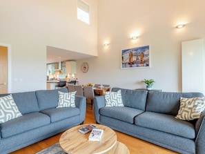En moderne stue med to grå sofaer, et træbord og et spiseområde med stole.