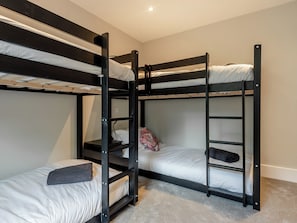 A bunk bed room with a carpeted floor and a light switch on the wall.