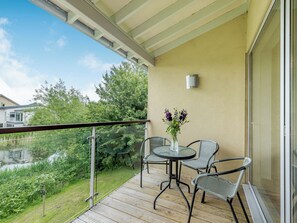 A balcony with a glass door, a small table with chairs, and a vase of flowers.