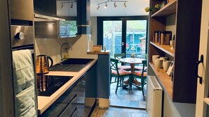 A modern kitchen with a built-in oven, a sink, and a dining area with a table and chairs.