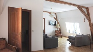 Un salón amplio con vigas de madera, un televisor y dos sofás.