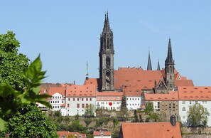 A historic building with multiple spires and a prominent clock tower, surrounded by traditional architecture.