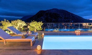 A rooftop pool area with lounge chairs and a view of a mountain.