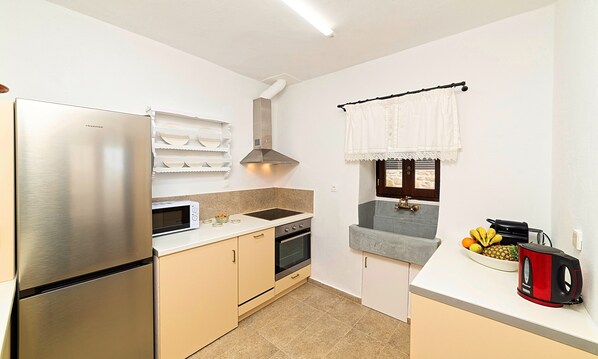 A compact kitchen with a stainless steel refrigerator, a microwave, a stove, and a sink.