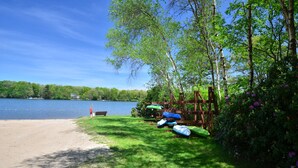 A lakeside campsite with a sandy beach, a wooden deck, and a row of sleeping bags. - Jim Thorpe, Bear Creek Lake, Cozy 3Br family friendly home- EV charging outlet (Jim Thorpe)