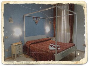 Un dormitorio con cama con dosel, mesita de noche, cómoda y estante de pared.