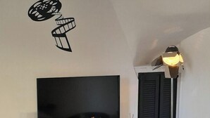 Een moderne woonkamer met een grote flatscreen-tv, een witte entertainmentkast, een houten tafel en een zwarte stoel.