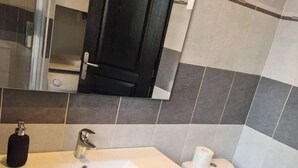Een badkamer met een witte wastafel, een spiegel, een zwarte deur en een toilet.