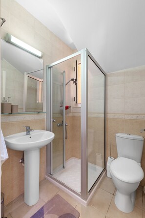 Une salle de bain moderne avec une douche à parois de verre, un lavabo blanc et des toilettes.