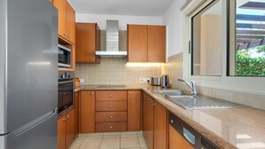 A modern kitchen with wooden cabinets, a stainless steel refrigerator, an oven, a microwave, and a dishwasher.