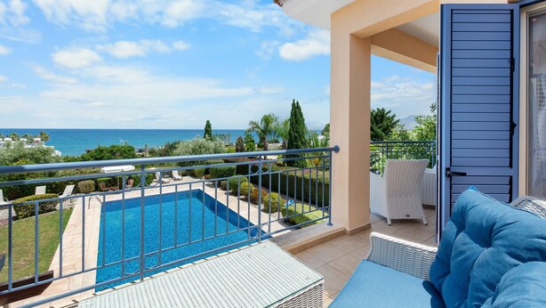 A balcony with a pool, outdoor furniture, and a view of the sea.