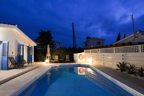 Una piscina al aire libre, sillones reclinables de piscina