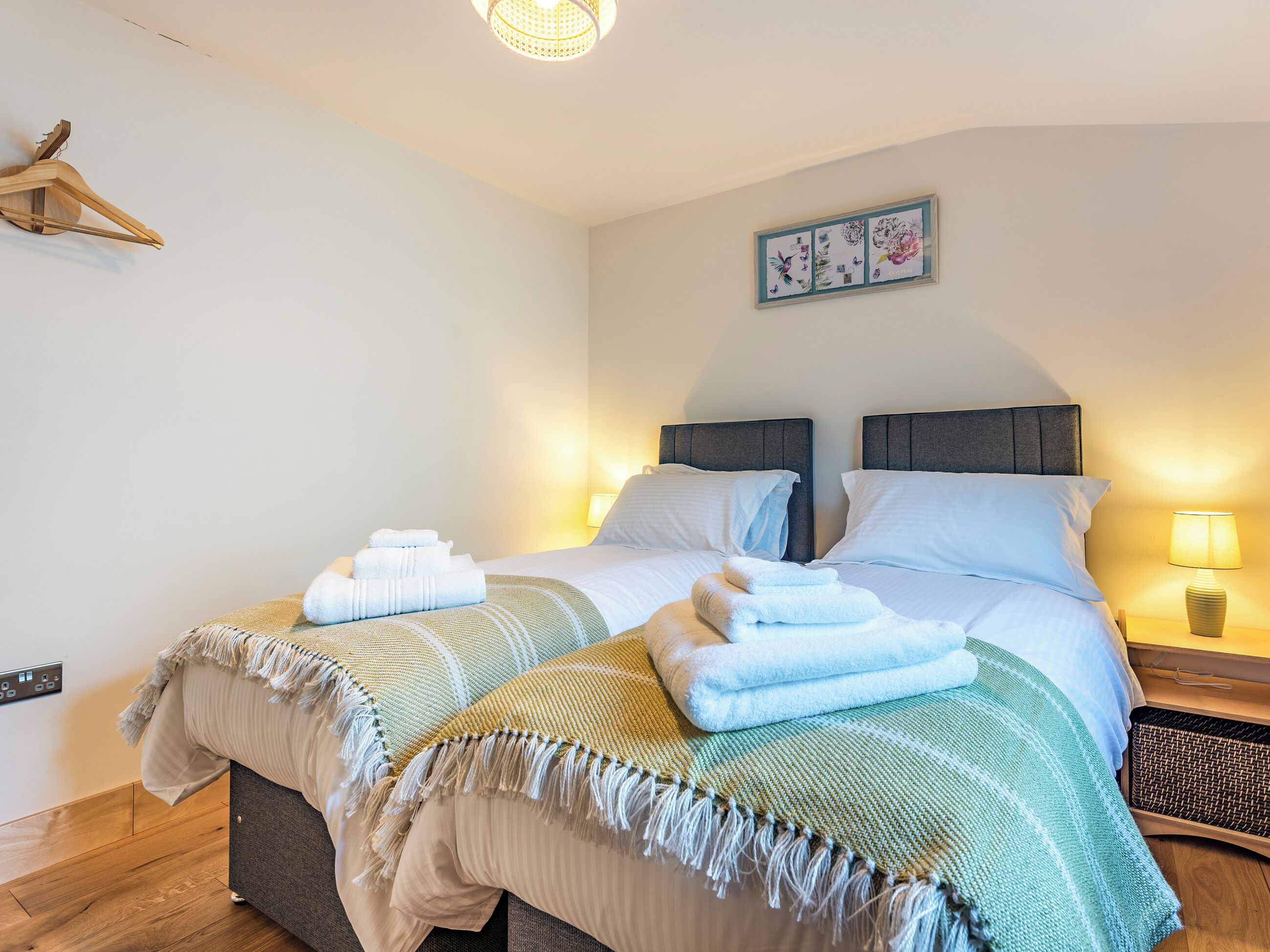 A double bed with two pillows, a bedside table with a lamp, and a wall-mounted light fixture.
