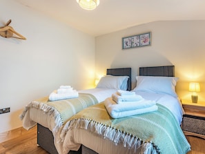 A double bed with two pillows, a bedside table with a lamp, and a wall-mounted light fixture. - Snowdrop Lodge -UK32959 (Ashford)