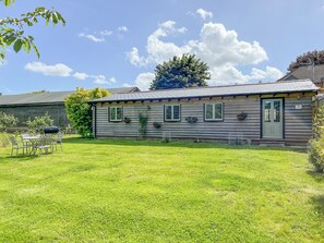 A wooden house with a front porch, a dining table and chairs, and a well-maintained lawn. - Snowdrop Lodge -UK32959 (Ashford)