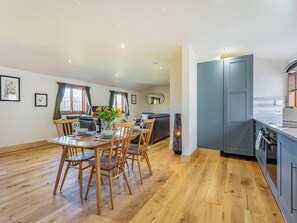 A spacious living area with a dining table set for four, a sofa, and a kitchen area with grey cabinets and a modern design. - Snowdrop Lodge -UK32959 (Ashford)