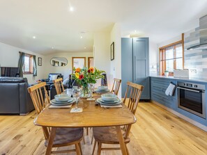 A modern kitchen with a dining area, wooden furniture, and a view of the living room. - Snowdrop Lodge -UK32959 (Ashford)