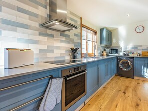 A modern kitchen with a built-in oven, microwave, and washing machine.