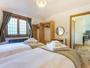 Ein Hotelzimmer mit zwei Betten, einem Holzschrank, einem Spiegel und Blick auf den Speisesaal.