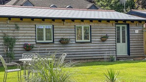 A wooden cabin with a front porch, a small table, and chairs.
