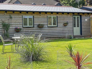 A wooden cabin with a front porch, a small table, and chairs. - Snowdrop Lodge -UK32959 (Ashford)