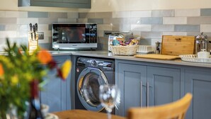 A compact kitchen with a microwave, toaster, and washing machine.