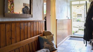A wooden bench with cushions, a mirror, and a door leading outside. - The Old Back Kitchen at Bonfield Ghyll Farm (Helmsley)