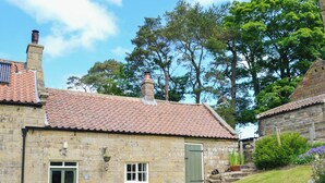 A stone building with a tiled roof, a green door, and a window. - The Old Back Kitchen at Bonfield Ghyll Farm (Helmsley)