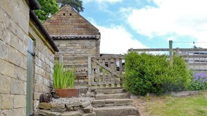 A stone building with a wooden staircase leading to a gated entrance. - The Old Back Kitchen at Bonfield Ghyll Farm (Helmsley)