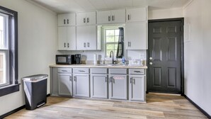 A kitchen with white cabinets, a microwave, and a sink. - The Bluebird: Modern 1 Bed, Large Peaceful Yard (Joplin)