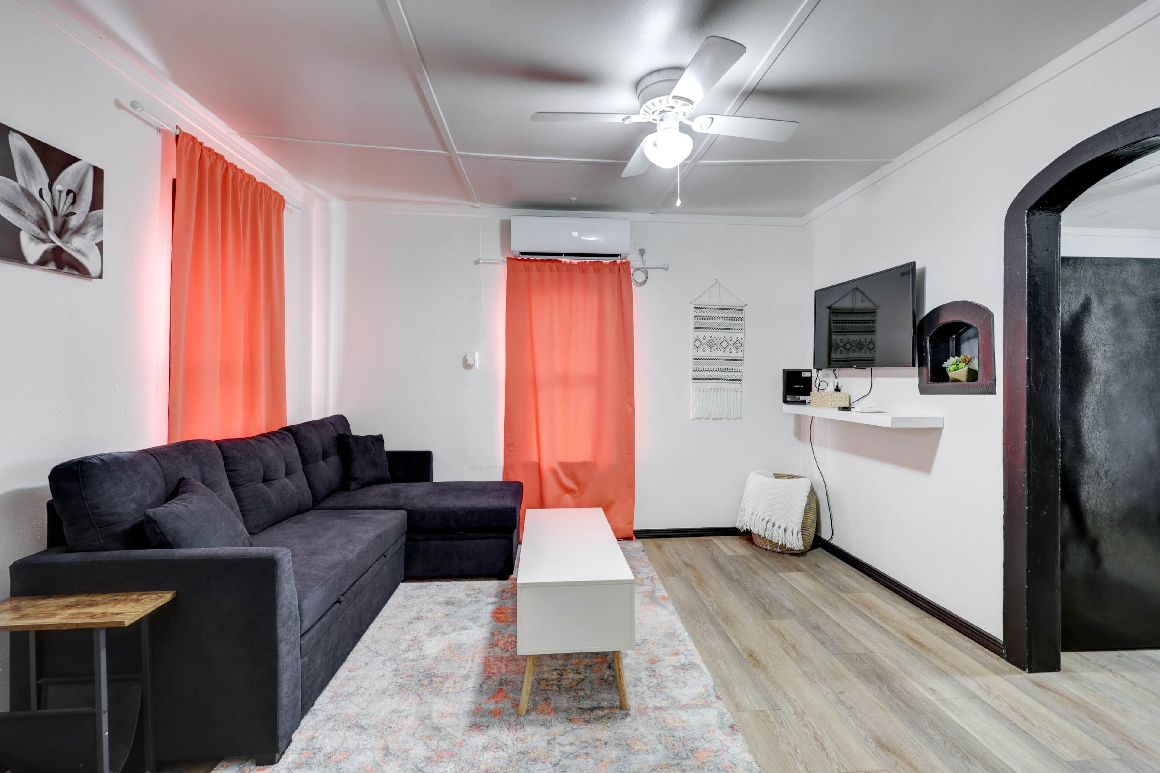 Een moderne woonkamer met een donkergrijze modulaire bank, een witte salontafel en een plafondventilator.