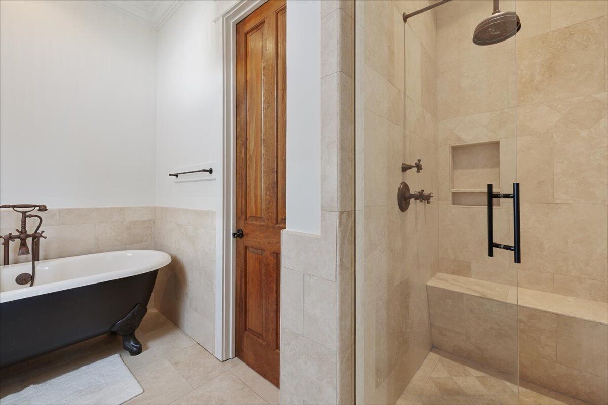 A bathroom with a freestanding bathtub, a shower enclosure, and a wooden door.