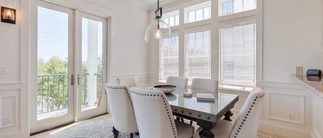 A dining area with a glass table, white chairs, and a pendant light.