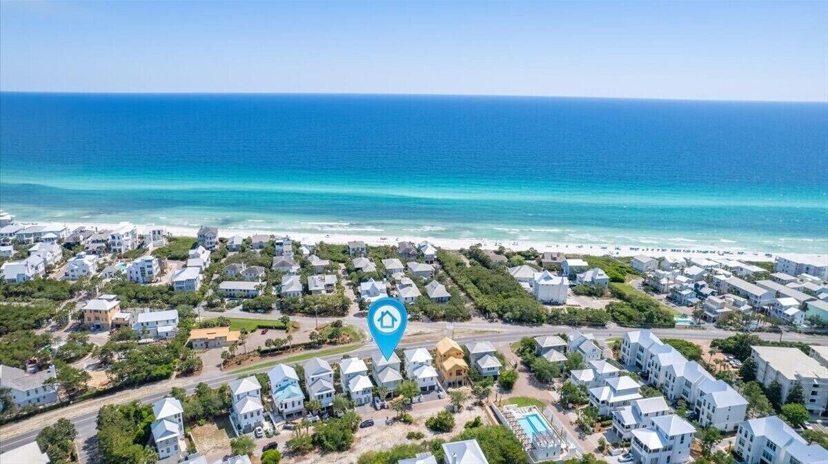 An aerial view of a coastal residential area with houses and a beach.