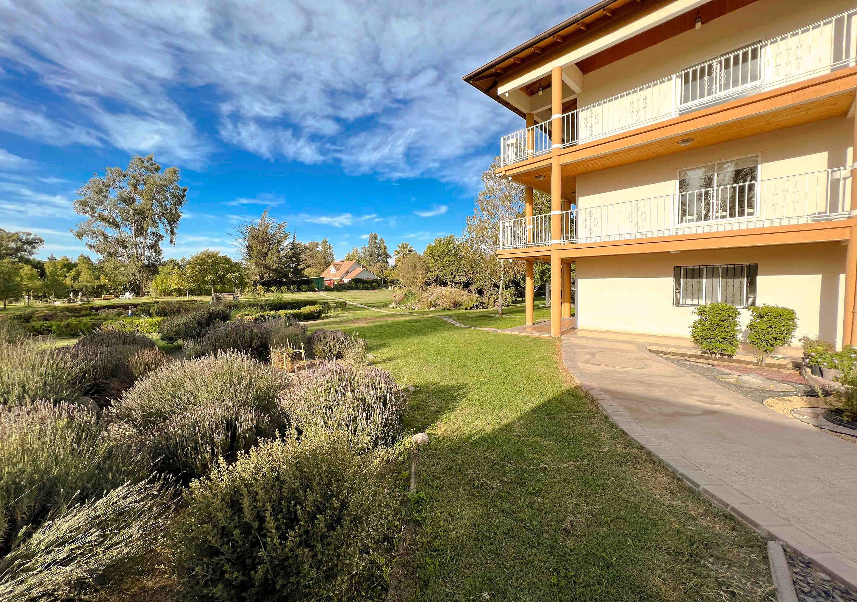 Ein zweistöckiges Gebäude mit Balkonen, umgeben von gepflegten Rasenflächen und Sträuchern.