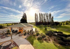 A building with a green roof, surrounded by a well-maintained garden with various plants and a paved driveway. - Hotel El Almendro (Buin)