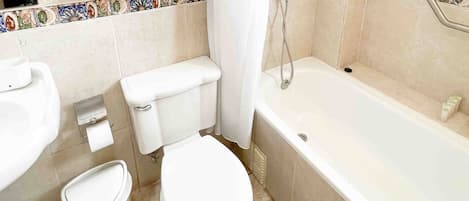 A bathroom with a toilet, bidet, sink, and bathtub.